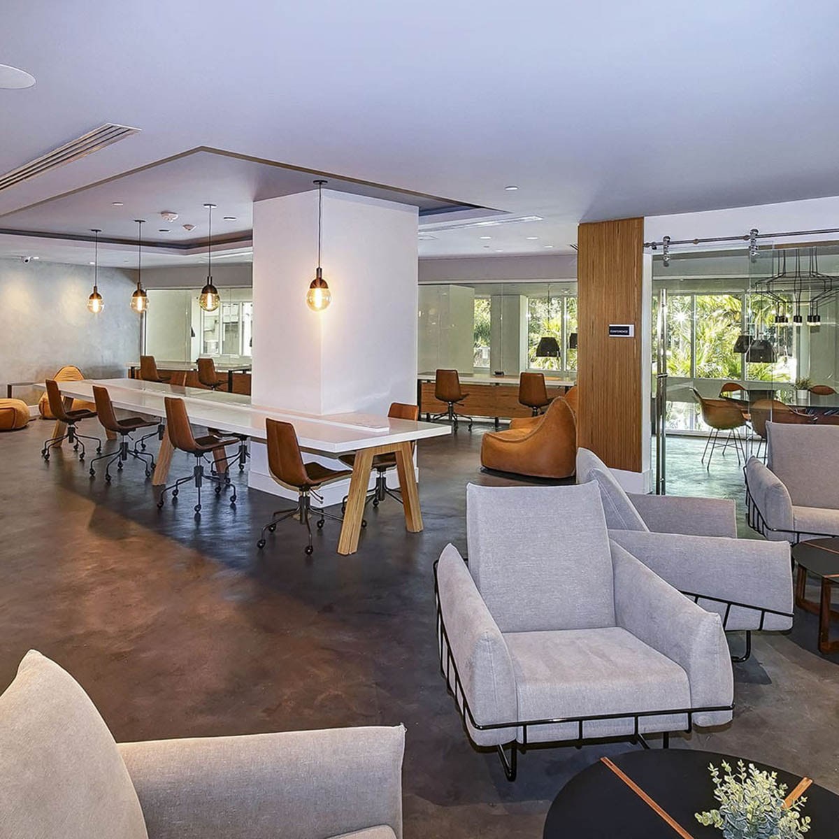 Lounge with plush seats, long tables, and large windows.