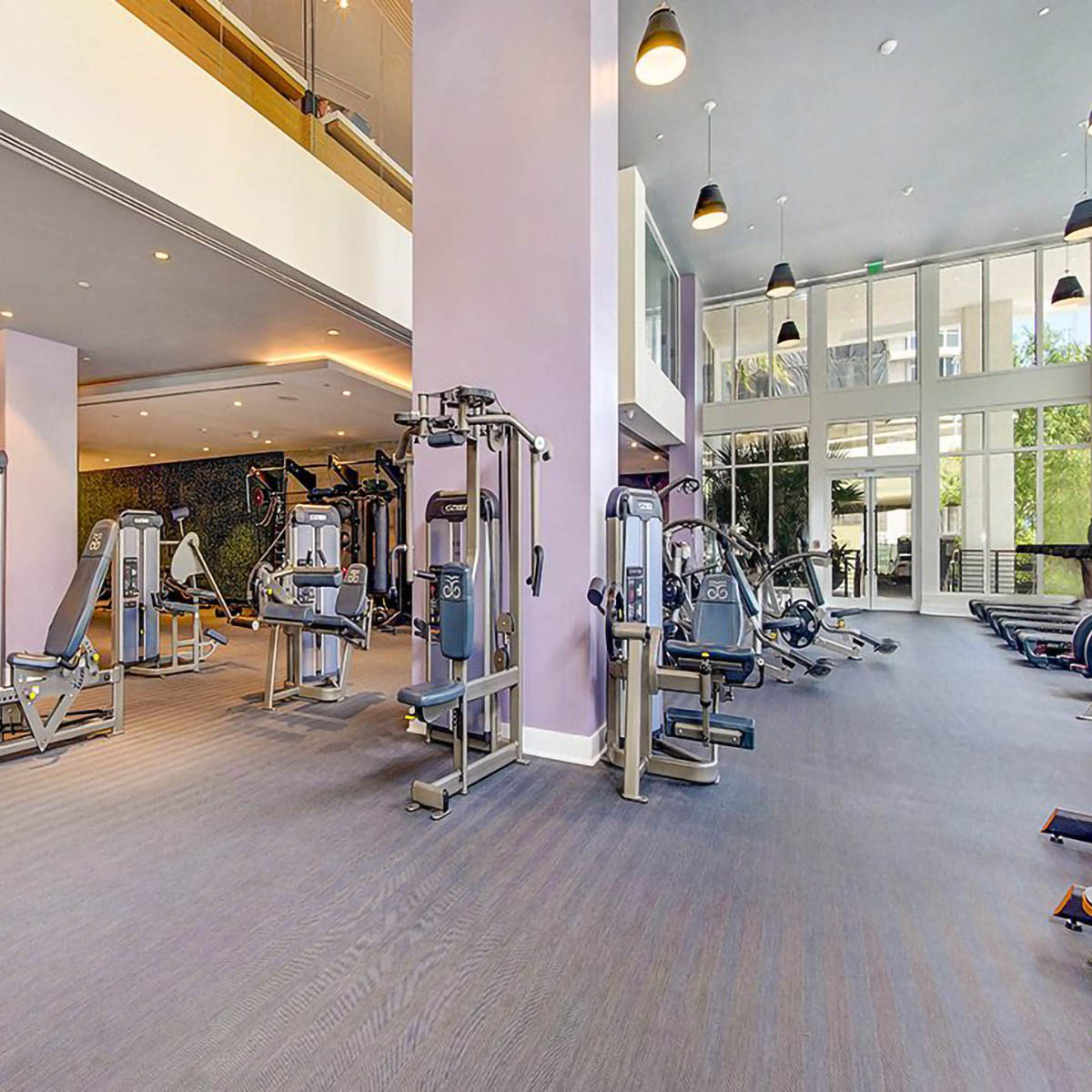 Fitness center with cardio machines, weight equipment, and tall windows.
