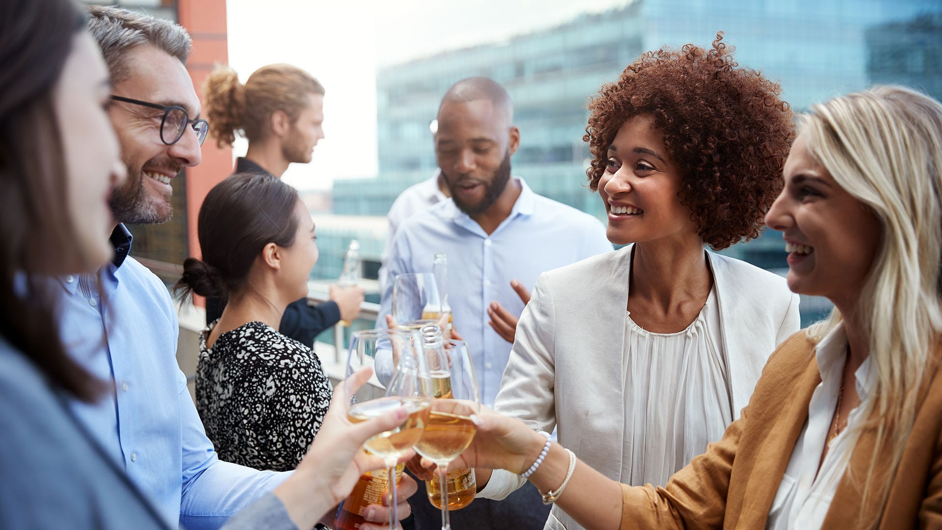 Friends toasting together on rooftop deck with wine glasses.