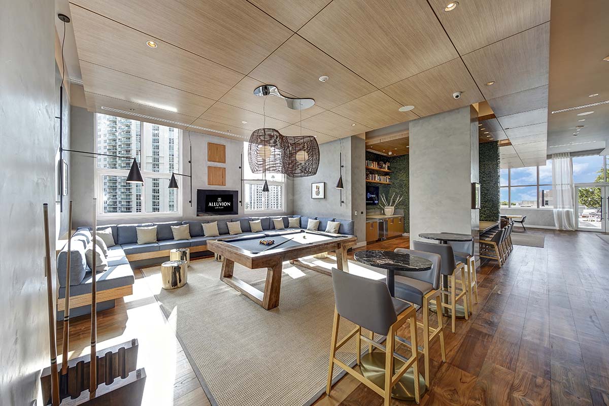 Alluvion apartments game room with billiards table, sectional couch, and community kitchen.