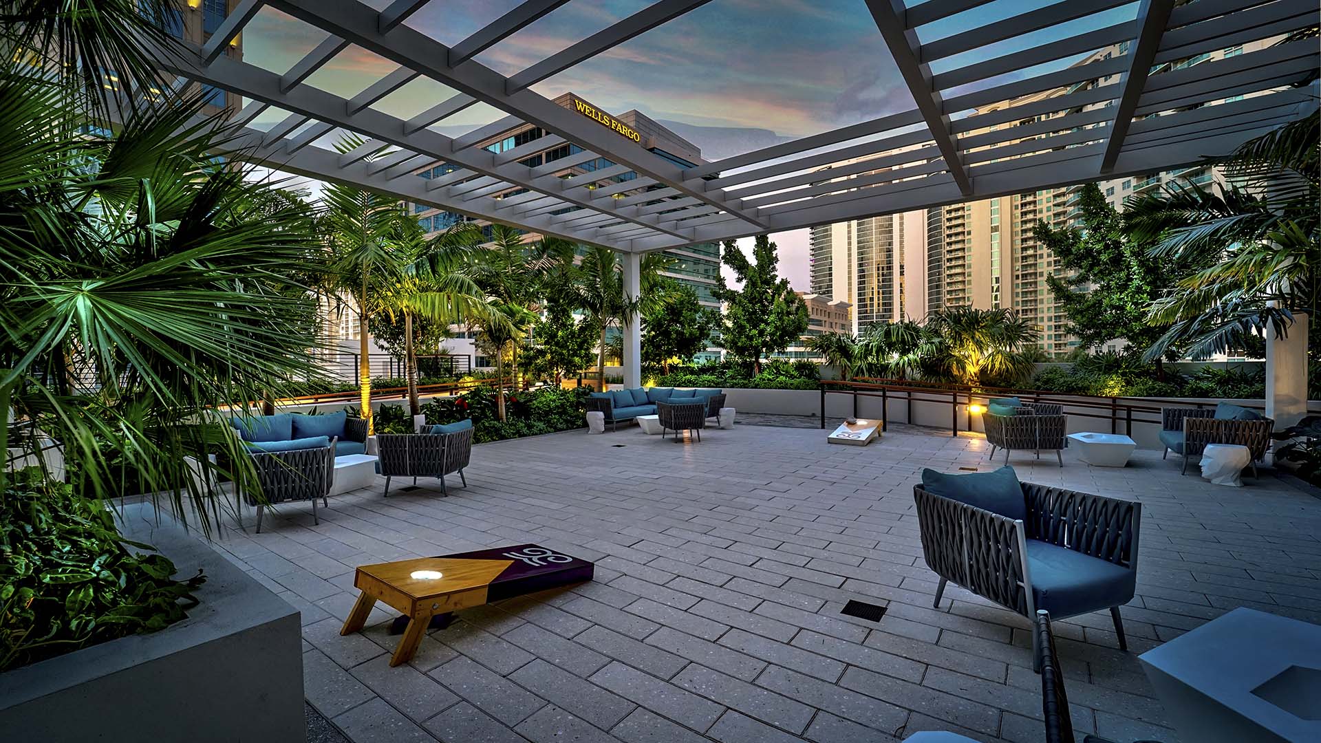 Rooftop patio at sunset with bag toss boards and plush seating.
