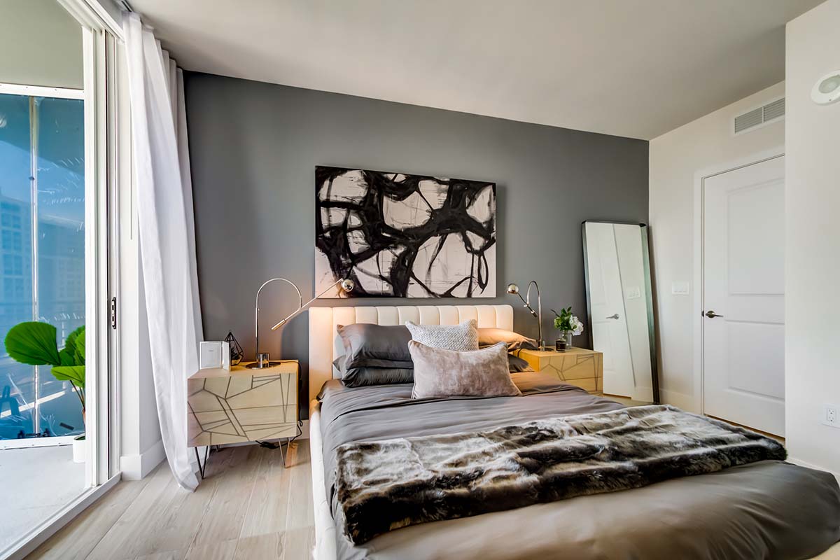 Bedroom with plush bed, bedside tables with lamps, and abstract artwork.