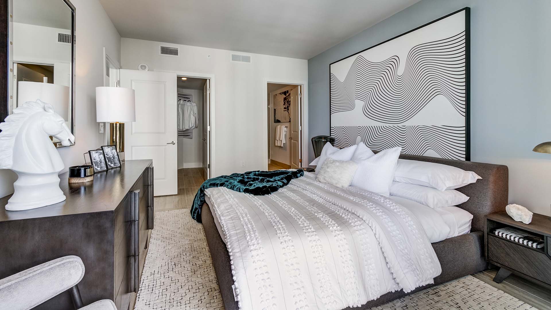 Bedroom with plush bed, elegant furniture, and large framed artwork.