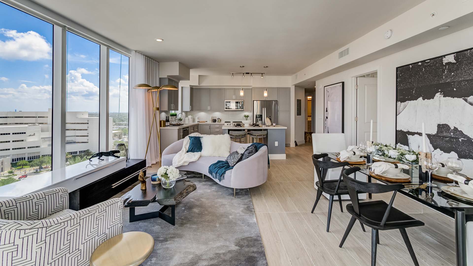 Apartment living room with plush seating, large windows, and elegant dining area.