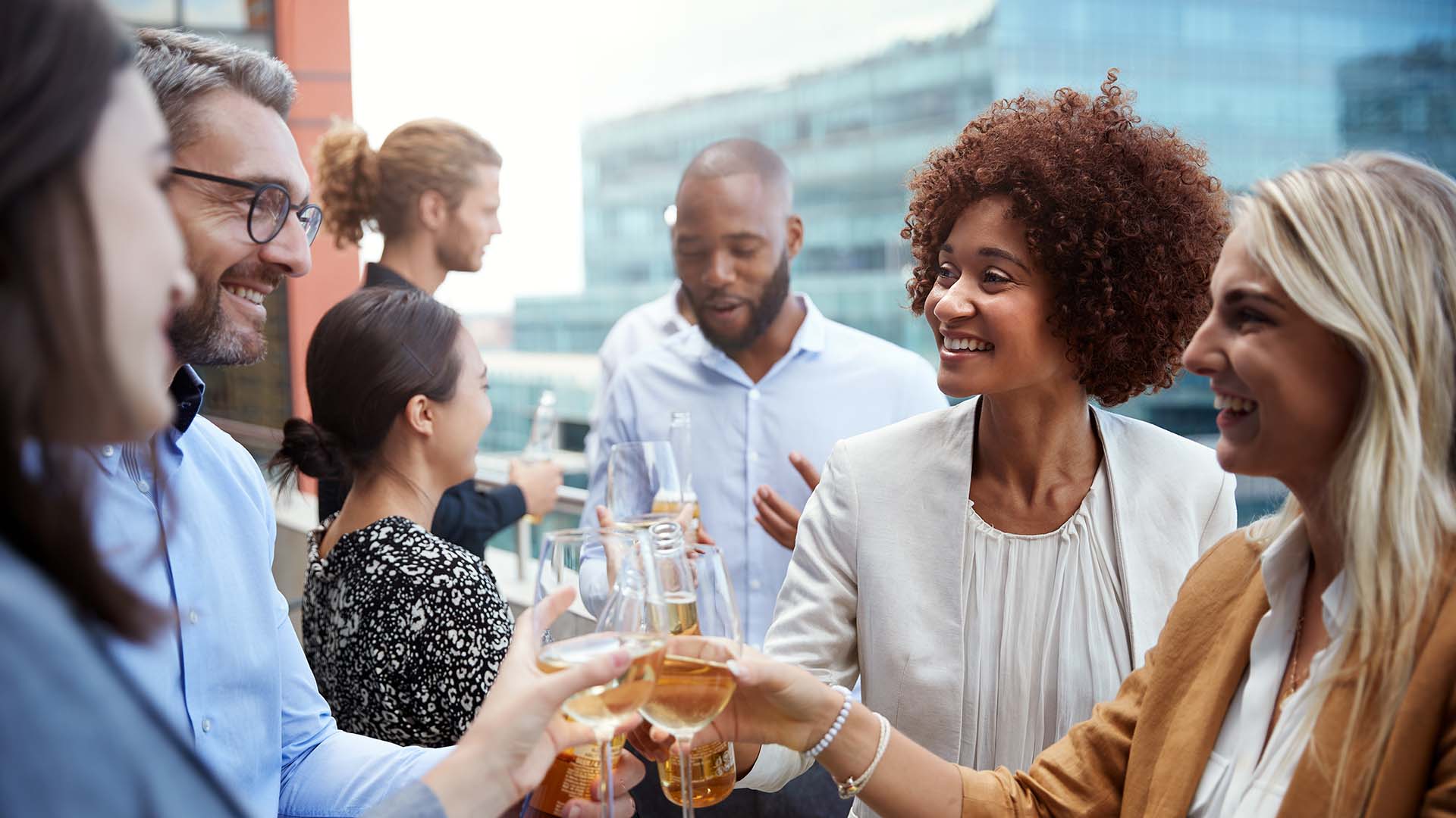 Friends toasting together on rooftop deck with wine glasses.